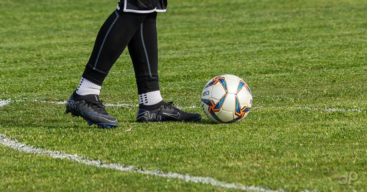 Portiere calcio dilettantistico con pallone ai piedi